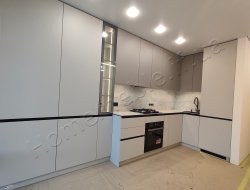 Світла сіра кухня з високими шафами, пеналами і темними акцентами